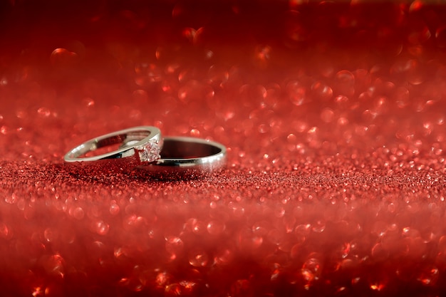 Premium Photo | Two wedding rings on red bokeh background