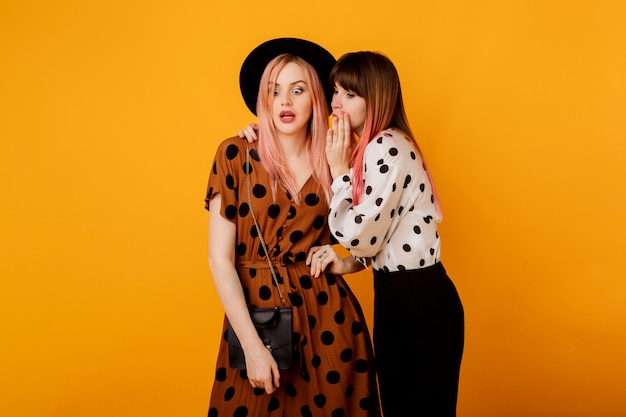 Free Photo Two Women Gossiping Over Yellow Wall In Stylish Vintage Outfit