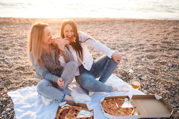 Premium Photo Two Young Beautiful Girlfriends Having Fun With Pizza