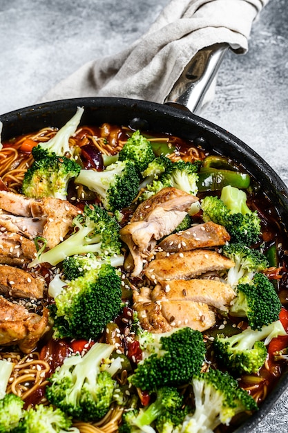 Udon stir-fry noodles with chicken in a pan. top view Premium Photo
