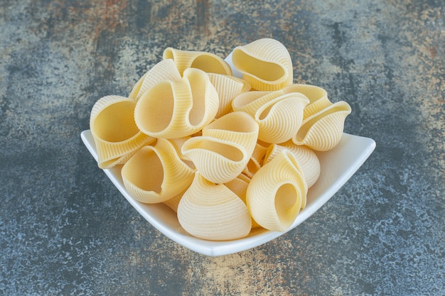 Free Photo | Unbaked pasta in the bowl, on the marble surface.