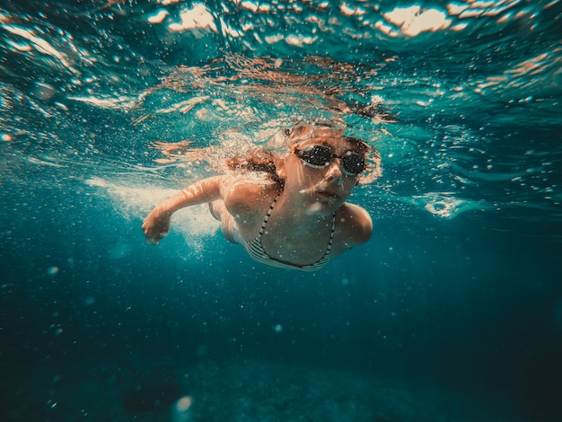 海で泳いでいる少女の水中写真 プレミアム写真