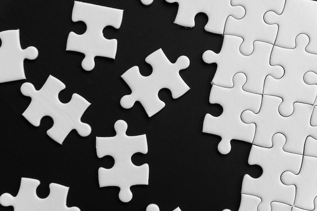 Premium Photo | Unfinished white jigsaw puzzle pieces on black background