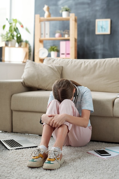 premium-photo-unhappy-teenage-girl-keeping-her-face-between-knees-while-sitting-on-the-floor