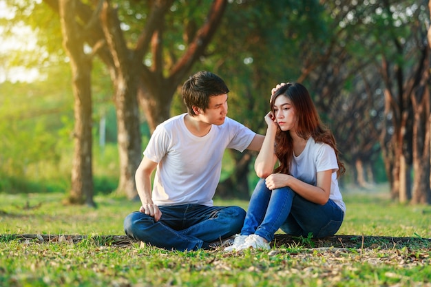 Unhappy Woman Sitting With A Concerned Guy Comforting Her In Park