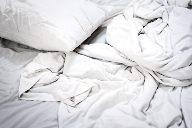 朝 ベッドの上に白い枕と寝室のしわの背景乱雑な毛布と朝の整えられていないベッド プレミアム写真