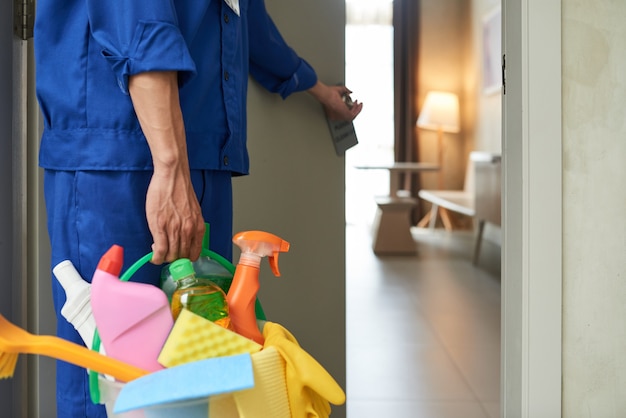 unrecognizable cleaner walking into hotel room with tools detergents 1098 17830