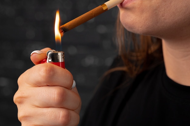 認識できない女性がライターでタバコに火をつける プレミアム写真