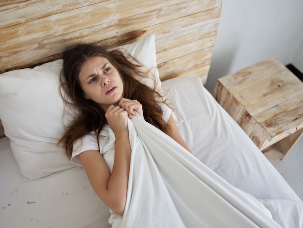 Premium Photo | Upset woman lies in bed under the covers and looks up