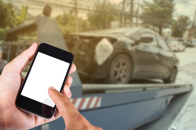 Using smartphone on hand with blurry background of black car on accident on the forklift. Premium Photo