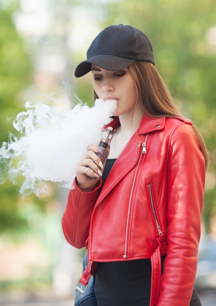 Vaping 야외에서 연기와 함께 젊은 아름 다운 여자 흡연 Vaping 전자 담배 증기 개념 프리미엄 사진 8755