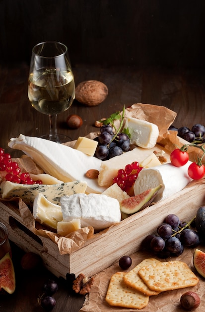 Premium Photo | Variety of different cheese with wine, fruits and nuts ...