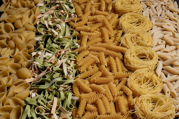 様々な種類と形の乾いたイタリアンパスタ イタリアのマカロニローフード背景やテクスチャ パスタ スパゲッティ スパイラルの形のパスタ プレミアム写真