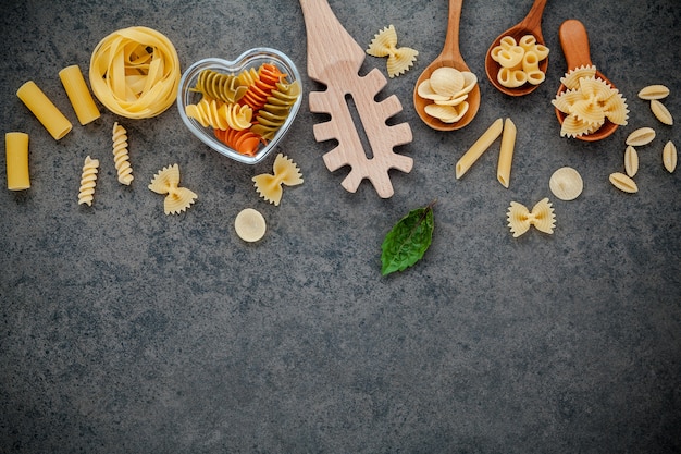 Premium Photo | Various kind of pasta on dark stone background with