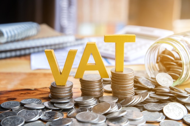 Vat concept. word vat with stacked coins there is a notebook calculator on the desk. Premium Photo