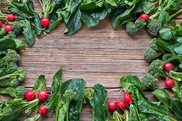 Vegetables background. radish, broccoli, spinach leaves with copy space in the middle. Premium Photo