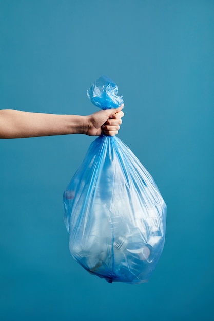 Premium Photo | Vertical image of female hand holding trash bag with ...