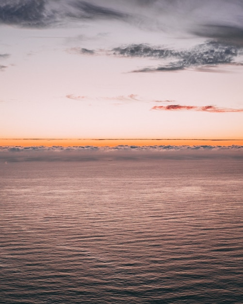 波とオレンジ色の地平線のある美しい海の景色の垂直方向の画像 無料の写真