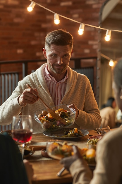 Premium Photo Vertical Portrait Of Handsome Mature Man Serving Food While Hosting Dinner Party With Friends And Family