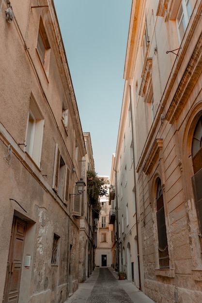 Free Photo Vertical Shot Of An Alleyway In The Middle Of Buildings Under A Blue Sky At Daytime