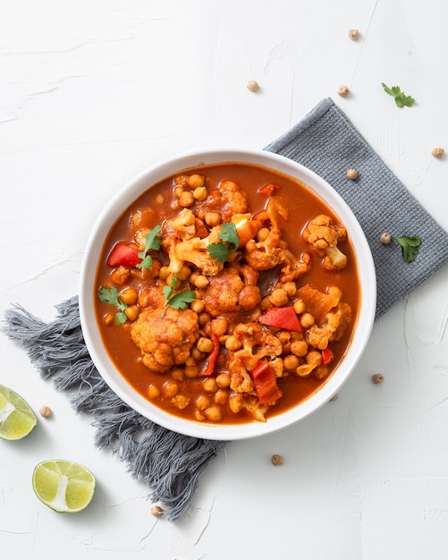 Vertical shot of chickpea curry chana masala with lime in a bowl on a white surf Free Photo