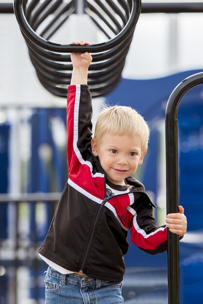 Vertical shot of a child hanging from a monkey bar Free Photo