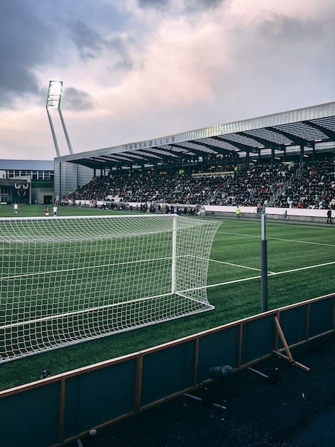 Vertical shot of crowded soccer stadium under cloudy sky Free Photo