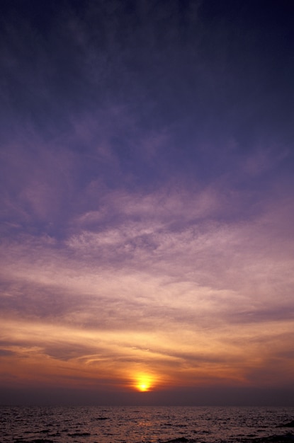 夕暮れ時の海の上の紫と黄色の空の垂直ショット 無料の写真