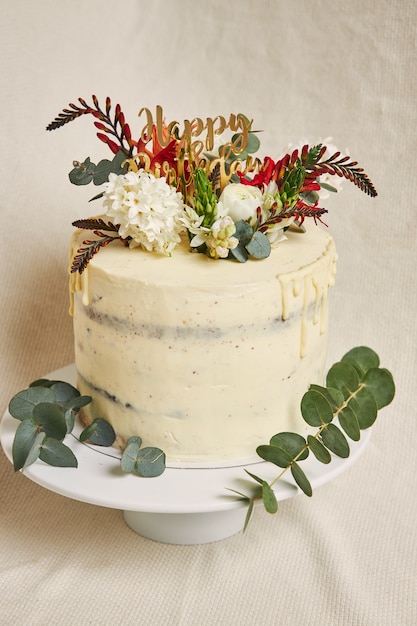 サイドにドリップが付いたトップケーキのおいしいバースデーホワイトクリームの花の垂直方向のビュー 無料の写真