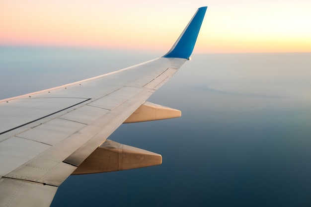 晴れた朝の海の風景の上を飛んでいる航空機の白い翼の飛行機からの眺め 空の旅と輸送の概念 プレミアム写真