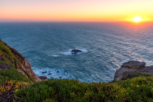 日没時のカボダロカの崖からの地平線と夕日の眺め ヨーロッパの最西端 ポルトガル シントラ プレミアム写真