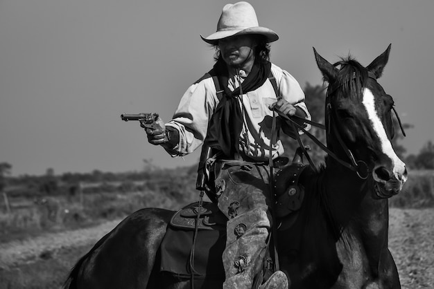 Premium Photo | Vintage image of a cowboy man riding a horse and a gun ...