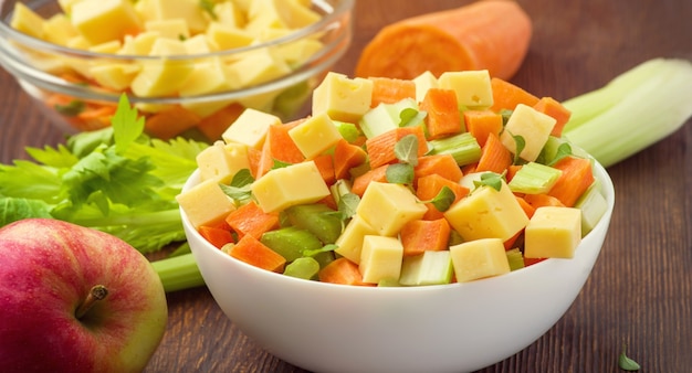 Vitamin salad of celery stalks, carrots, apples and cheese. vegetable salad with cheese cut into cubes in a plate and a number of ingredients are. Premium Photo