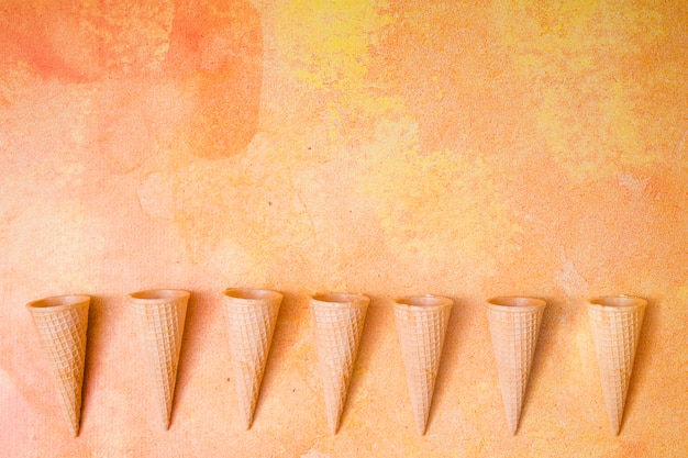 Waffle cones in row on multicolored background | Free Photo