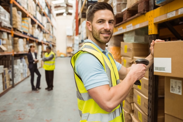 Warehouse worker scanning box while smiling at camera Premium Photo