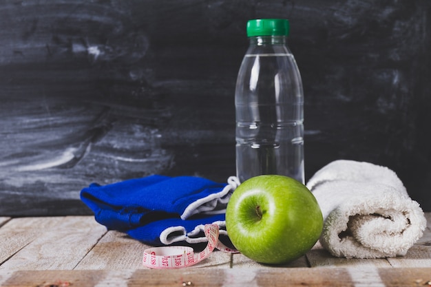 Free Photo | Water bottle with towel, apple and tape measure