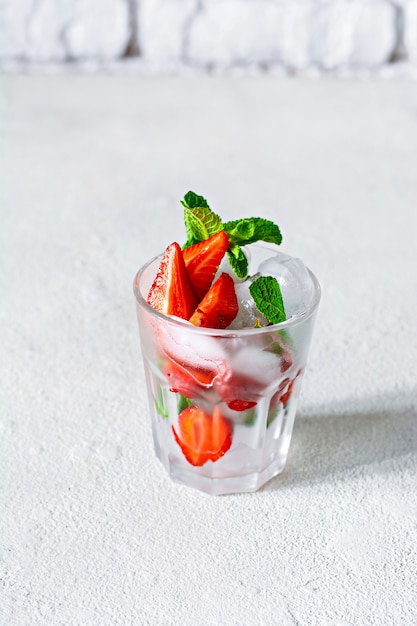 Premium Photo Water With Ice Strawberry Syrup Fresh Strawberries And Mint In A Glass Cup On A White Background