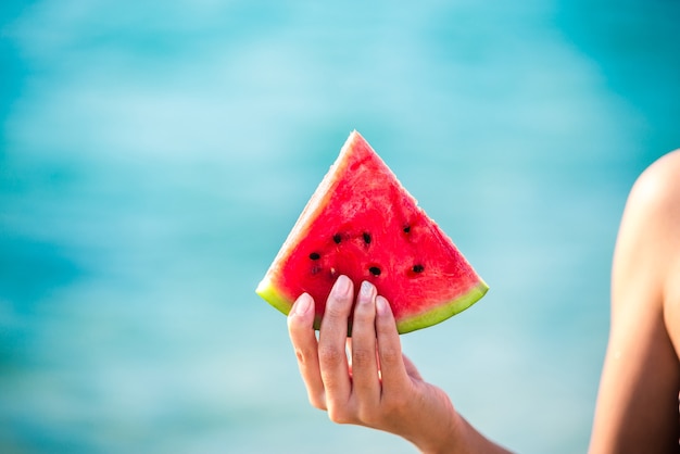 Premium Photo | Watermelon slice in woman hand over sea - pov