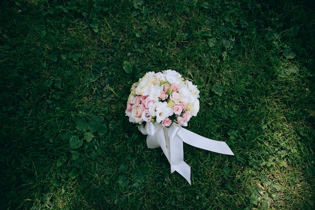 白とピンクのバラのウェディングブーケは緑の草の上にあります プレミアム写真