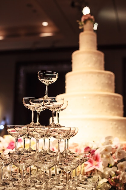結婚式の舞台でテーブルの上にシャンパングラスタワー付きのウェディングケーキ プレミアム写真