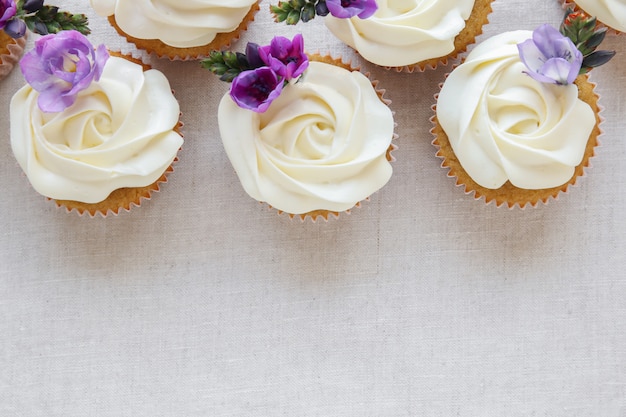 紫色の食用花とホイップクリームのフロスティングバニラカップケーキ プレミアム写真