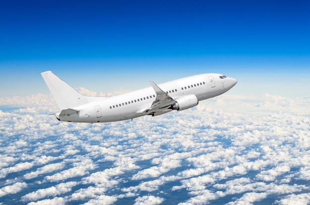 Premium Photo | White airplane flies high in the sky above the clouds ...