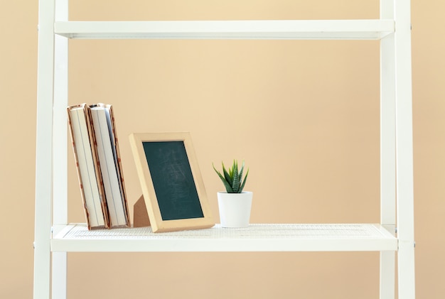 Premium Photo | White bookshelf with books and stationery against beige ...