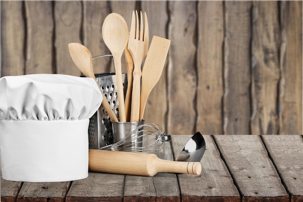 Premium Photo | White chef hat and utensils on table