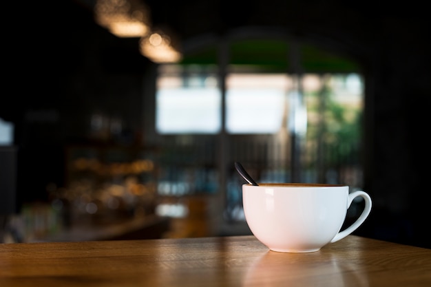 White coffee cup over wooden desk in coffee shop Photo | Free Download