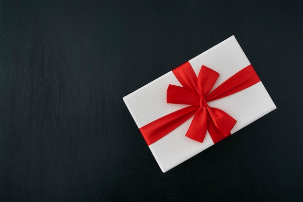 Premium Photo | White gift box with red ribbon on black background. top ...