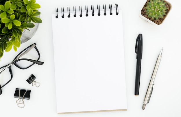 White office desk table with blank notebook page and supplies. top view, flat lay. Premium Photo