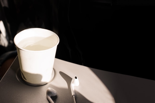 Premium Photo White Paper Cup Of Water And Headphones On A Folding Table In An Airplane Drinks On The Plane Dehydration In Flight