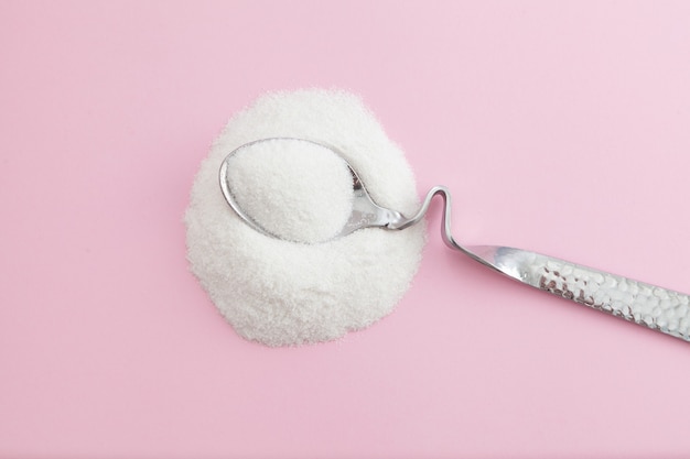 Premium Photo | White powder and silver spoon on pink background with ...