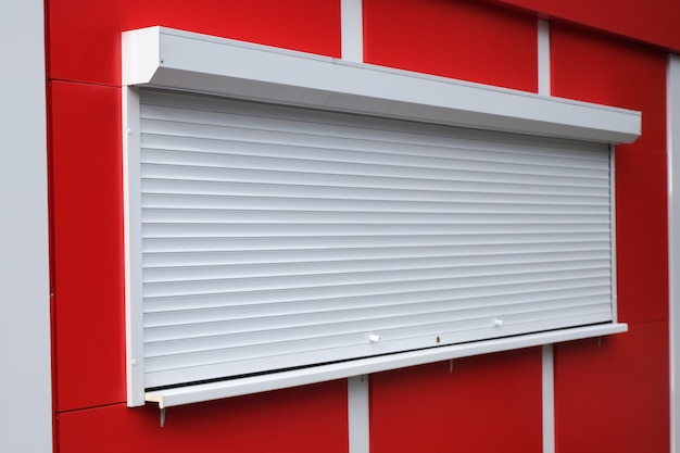 White roller shutters at a red kiosk. Premium Photo